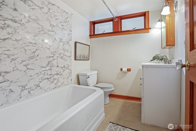 full bathroom featuring baseboards, toilet, vanity, and a tub to relax in