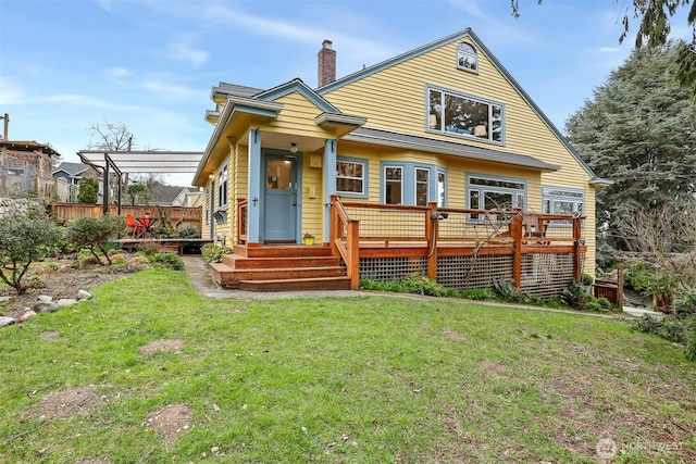 view of front facade with a chimney, a deck, a front lawn, and fence