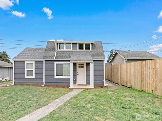 view of front facade featuring a front lawn, roof with shingles, and fence