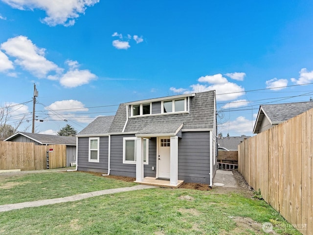 view of front of property featuring a fenced backyard, a front lawn, and roof with shingles