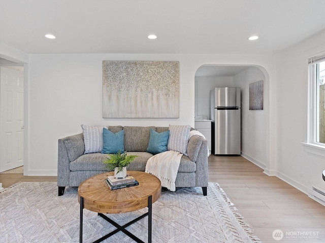 living room with recessed lighting, arched walkways, and light wood-type flooring