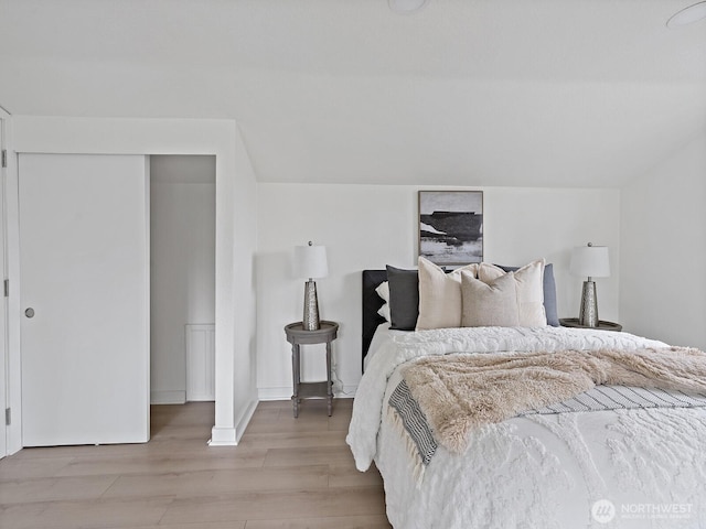 bedroom with lofted ceiling and light wood finished floors