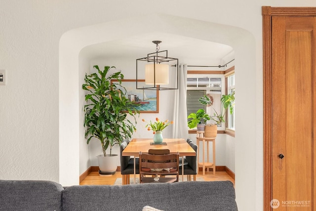 interior space featuring light wood-type flooring, arched walkways, and baseboards