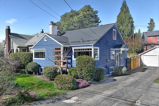 view of front facade with driveway, a chimney, and an outdoor structure