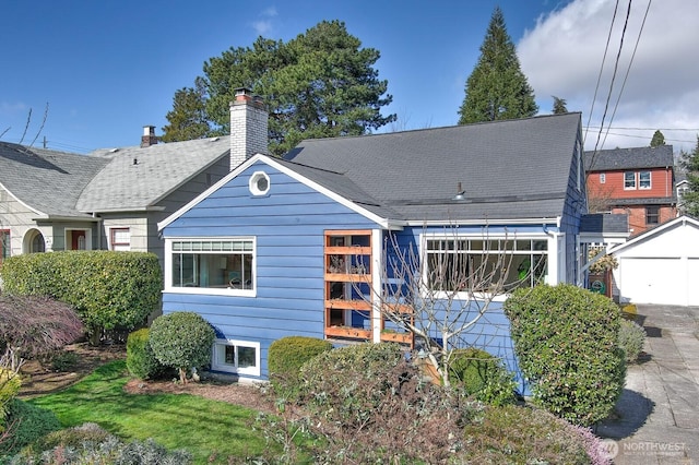 back of house with an outbuilding and a chimney