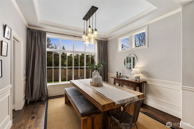 dining area with dark wood-style flooring, wainscoting, crown molding, a notable chandelier, and a raised ceiling