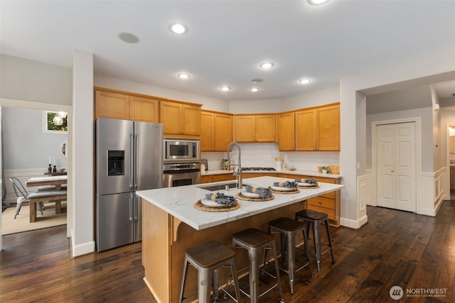 kitchen with dark wood-type flooring, a sink, light stone counters, recessed lighting, and appliances with stainless steel finishes