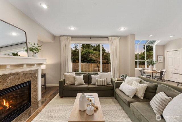 living room with recessed lighting, wood finished floors, baseboards, and a premium fireplace