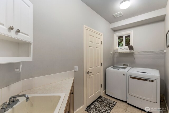 laundry area featuring visible vents, a sink, cabinet space, separate washer and dryer, and light tile patterned floors