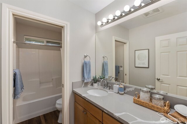 bathroom featuring visible vents, toilet, wood finished floors, tub / shower combination, and vanity