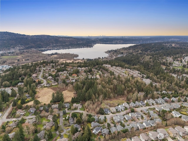 aerial view at dusk featuring a water view and a residential view