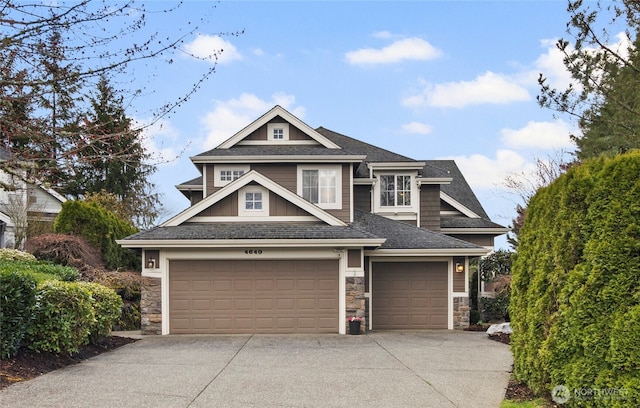 craftsman-style house featuring stone siding, an attached garage, concrete driveway, and a shingled roof