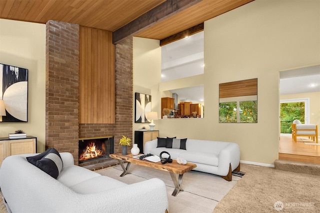 living area with beam ceiling, light carpet, high vaulted ceiling, wooden ceiling, and a brick fireplace