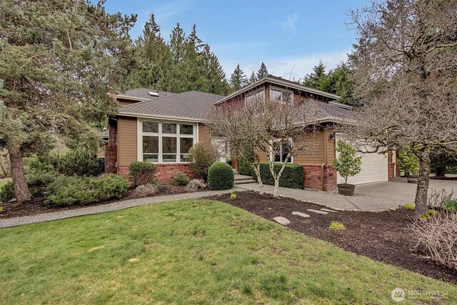 view of front of house featuring roof with shingles, concrete driveway, a front yard, a garage, and brick siding