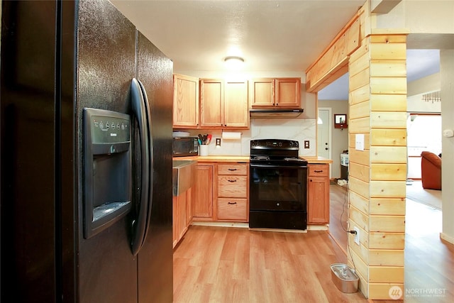 kitchen featuring black appliances, light wood-type flooring, and light countertops