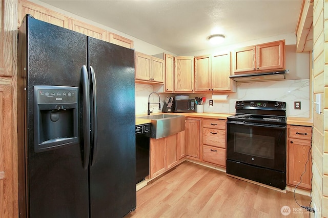 kitchen with black appliances, tasteful backsplash, light wood finished floors, and a sink