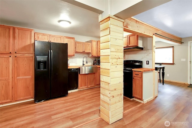 kitchen featuring black appliances, tasteful backsplash, light wood-type flooring, and a sink