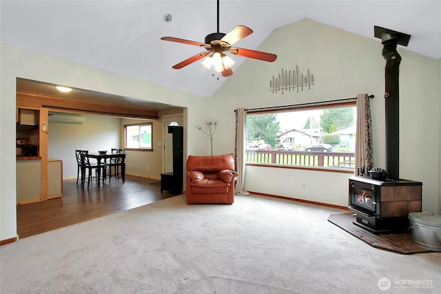 living area with a wealth of natural light, carpet flooring, and a wood stove