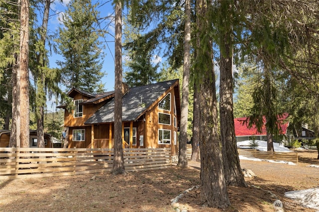 chalet / cabin featuring a porch, fence, and a shingled roof