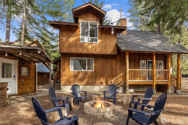 back of property with a chimney, roof with shingles, and an outdoor fire pit