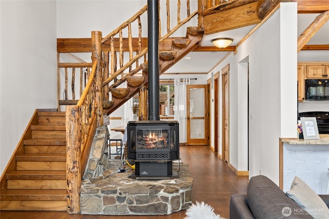 stairway featuring a wood stove, wood finished floors, and baseboards