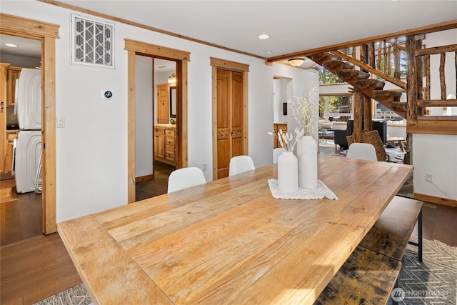 dining area with stairs, stacked washer / dryer, wood finished floors, and ornamental molding