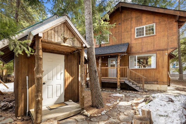 view of front of home with an outdoor structure and roof with shingles