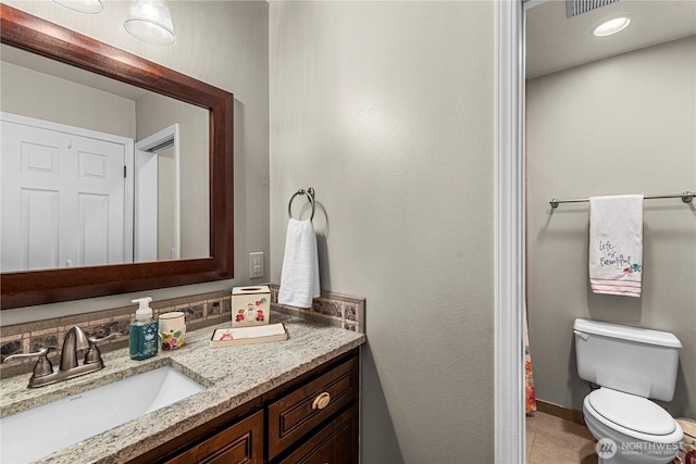 bathroom with toilet, vanity, and baseboards