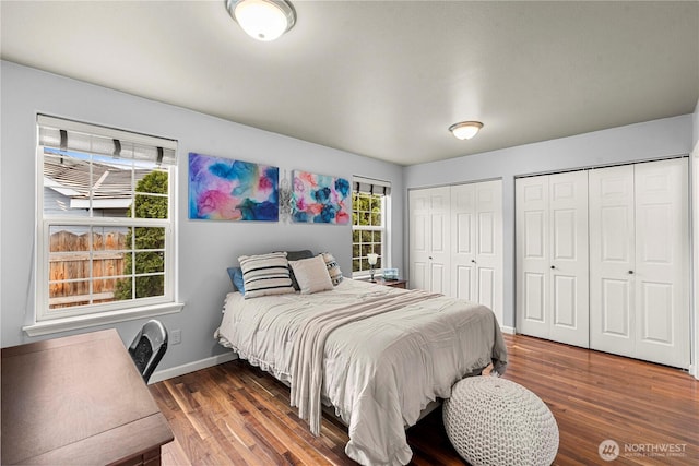 bedroom featuring baseboards, multiple closets, and wood finished floors