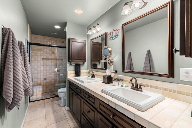 bathroom with a sink, toilet, double vanity, and a shower stall