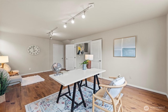 office area with baseboards, wood finished floors, and rail lighting