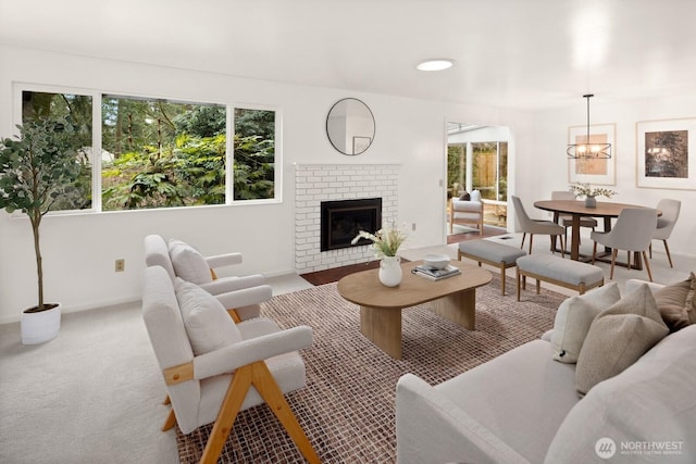 living room with an inviting chandelier, a fireplace, baseboards, and carpet