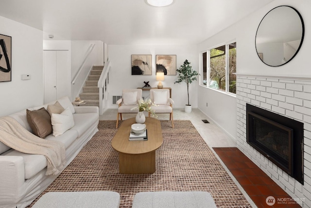 living area with stairs, a brick fireplace, visible vents, and baseboards