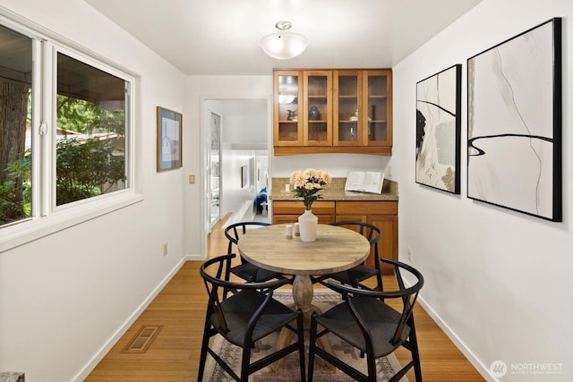 dining room with visible vents, light wood-type flooring, and baseboards