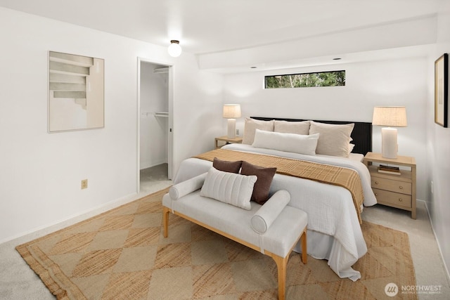 bedroom featuring a closet, baseboards, light colored carpet, and a spacious closet