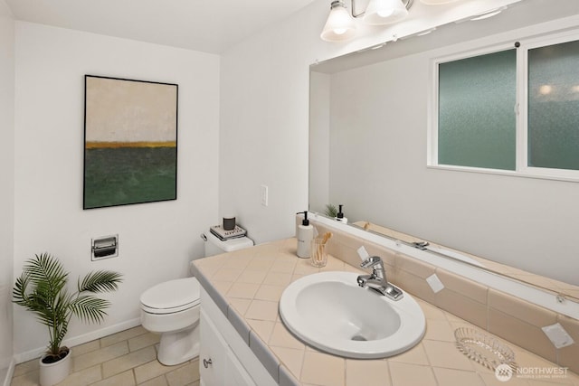 bathroom with tile patterned floors, toilet, vanity, and baseboards