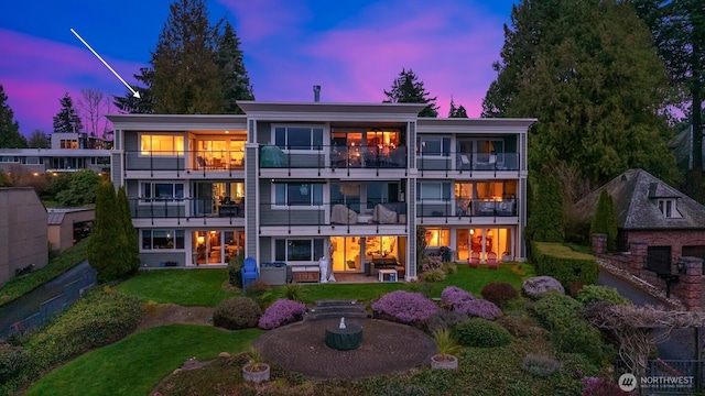 back of property at dusk featuring a patio and a lawn