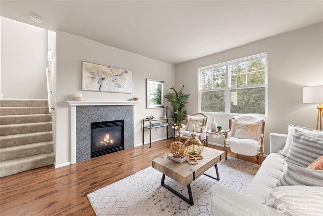 living area with stairway, baseboards, a glass covered fireplace, and wood finished floors