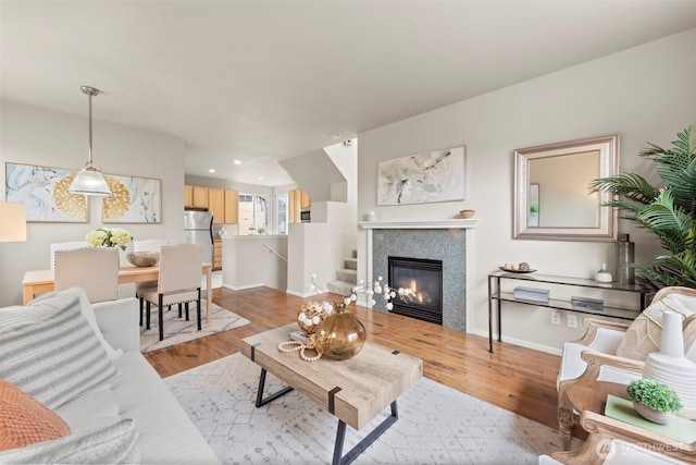 living room with light wood finished floors, a glass covered fireplace, recessed lighting, and baseboards