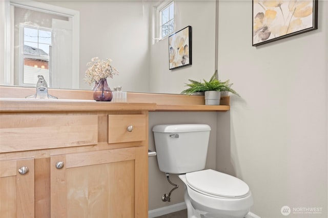 bathroom featuring toilet, vanity, and baseboards