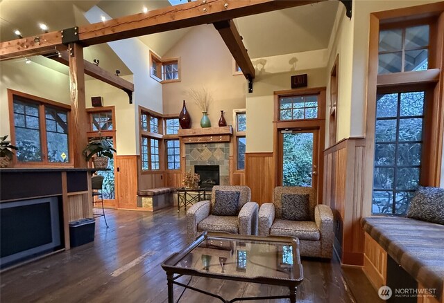 living room with wood finished floors, high vaulted ceiling, a fireplace, wainscoting, and beamed ceiling