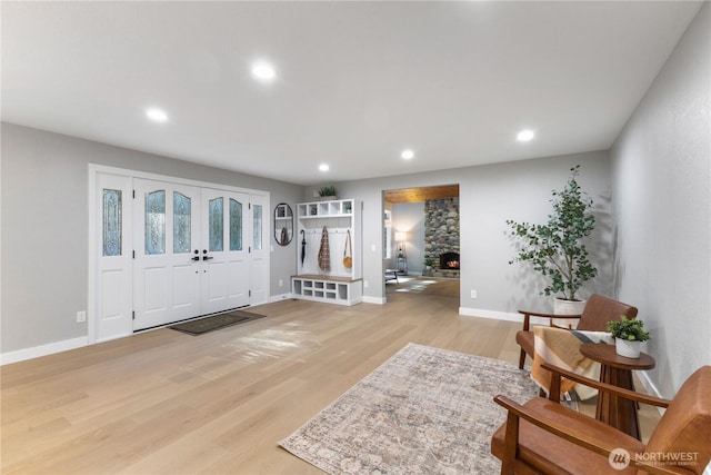 entrance foyer with recessed lighting, light wood-type flooring, baseboards, and a stone fireplace