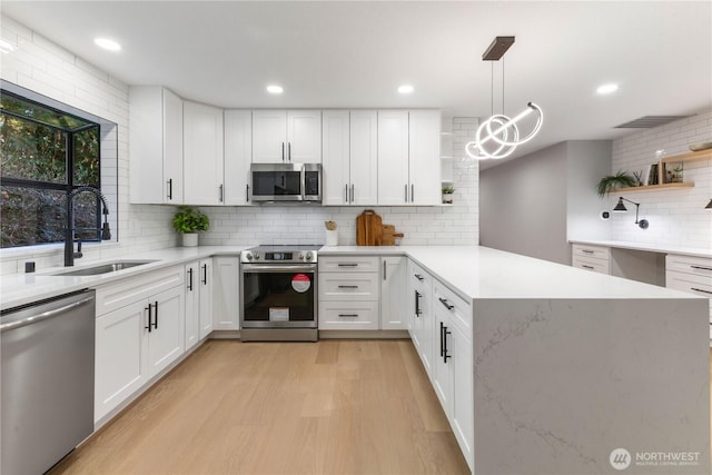 kitchen featuring a sink, a peninsula, stainless steel appliances, and open shelves