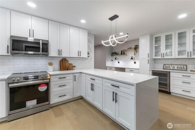 kitchen featuring beverage cooler, decorative backsplash, light wood-style flooring, appliances with stainless steel finishes, and white cabinets