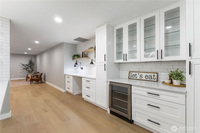 bar with light wood finished floors, visible vents, backsplash, baseboards, and wine cooler