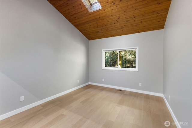 spare room featuring a skylight, visible vents, baseboards, and light wood finished floors