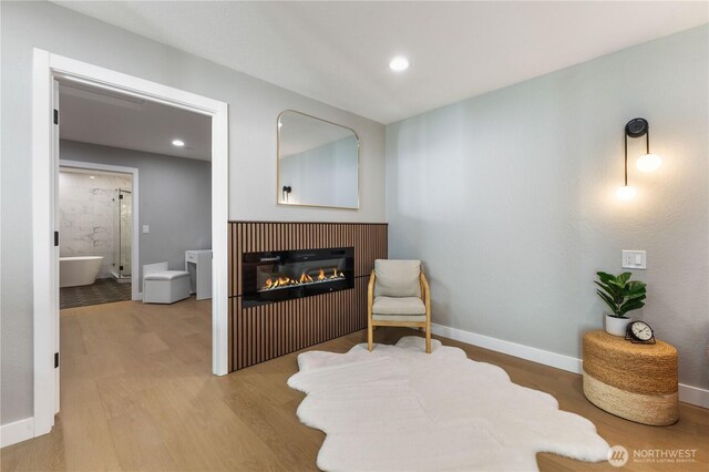 sitting room with a glass covered fireplace, recessed lighting, wood finished floors, and baseboards