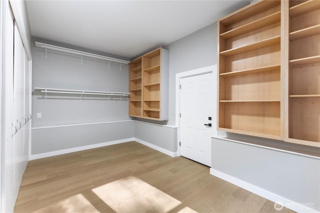 walk in closet with attic access and wood finished floors