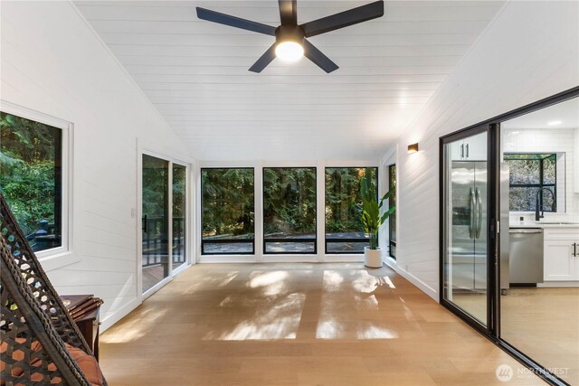 unfurnished sunroom with ceiling fan, wooden ceiling, vaulted ceiling, and a sink