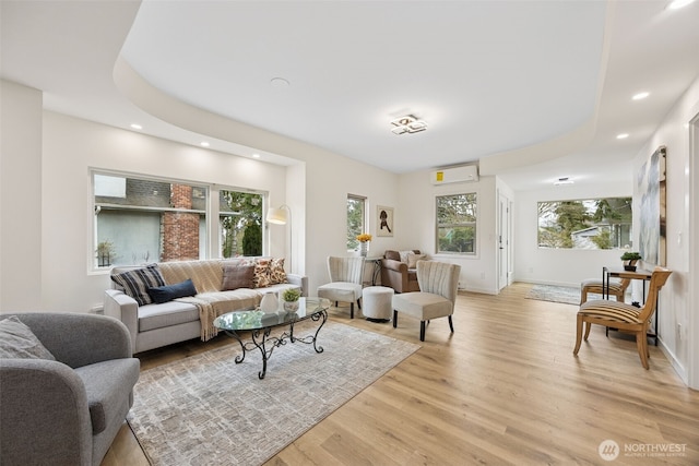 living area featuring light wood-style flooring, recessed lighting, baseboards, and a wall mounted air conditioner